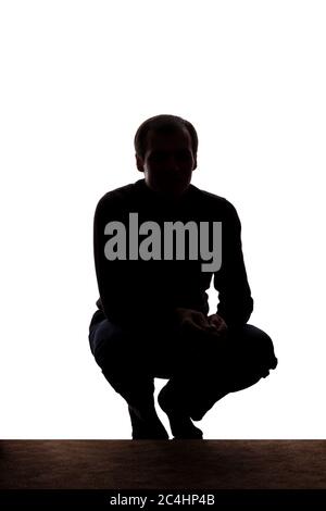 Portrait of a young man squatted down, front view - silhouette Stock Photo