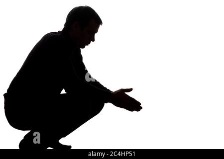 Portrait of a young man squatted down, side view - silhouette Stock Photo