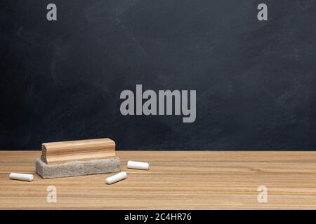 Back to school background concept. Chalk and eraser on wooden desk and chalkboard background. Copy space Stock Photo