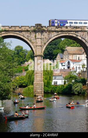 A Northern Rail train crosses Knaresborough Viaduct which spans the River Nidd. The river is popular with tourists using rowing boats for hire nearby Stock Photo