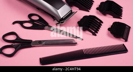 hairdressing tools on a pink background, hair clipper, straight and thinning barber scissors and comb. Stock Photo