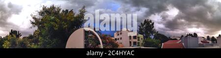 Panorama of monsoon clouds over houses in Bangalore, India. Dark stormy clouds, buildings visible. Stock Photo