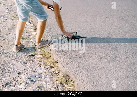 A young guy launches a drone. Preparing the quadcopter for takeoff. Stock Photo