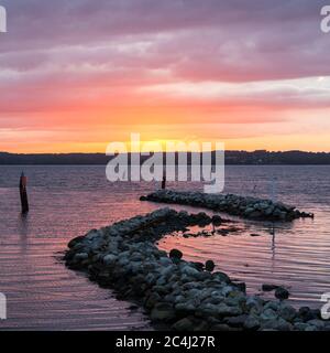 Breakwater rocks at the Baltic Sea during dramatic colourful sunset Stock Photo