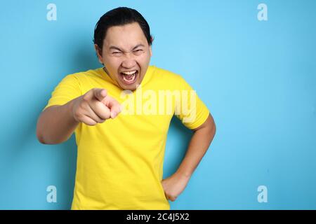 Portrait of funny Asian man laughing hard and pointing forward, bully expression, close up head shot with selective focus Stock Photo
