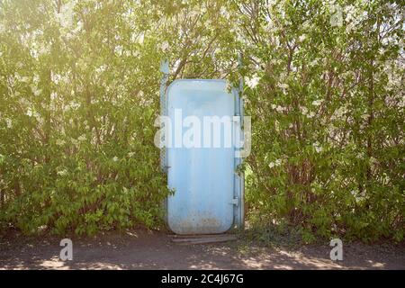 blue iron door surrounded by green trees. Light effects. Stock Photo
