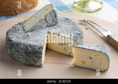 Whole fresh French Rochebaron cheese and pieces on a cutting board Stock Photo