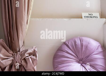 Interior decor of a popular, London-based hotel room. Showing a No Smoking sign on a ledge above a sitting area near an out of view sash window. Stock Photo