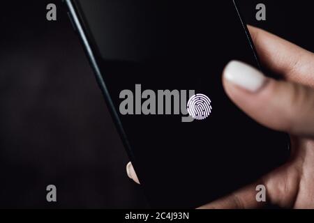 Hands holding smartphone with fingerprint scanner in the screen. Stock Photo