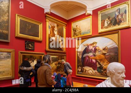 Visitors looking at large framed paintings on a wall at Leeds Art Gallery, Leeds, West Yorkshire, England, UK. Stock Photo