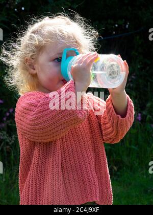 Toddler drinking from a soft straw spout water bottle, UK Stock Photo