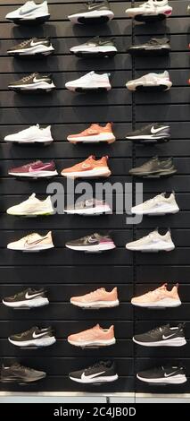 Shop display of a lot of Sports shoes on a wall. A view of a wall of shoes inside the store. Modern new stylish sneakers running shoes for men and wom Stock Photo