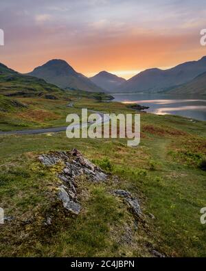 Winding Single Track Road Leading Through Green Secluded Countryside With Beautiful Sunrise. Wastwater, Lake District, UK. Stock Photo