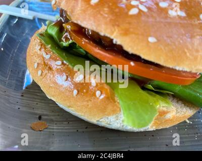 Close up of isolated juicy beef burger with sesame bun, green lettuce, onions and tomato Stock Photo
