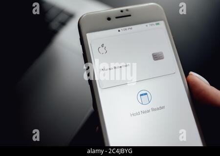 Womans hand holding the iPhone X with Apple Card on the screen. Stock Photo