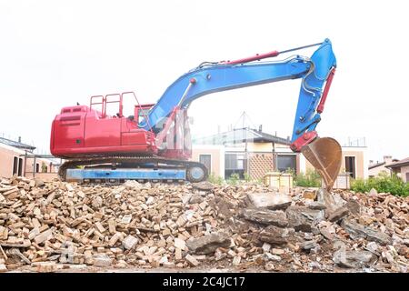 Crawler bulldozer over the rubble of a building in the residential area - Crawler excavator machine with bucket for removal from site to clear the are Stock Photo