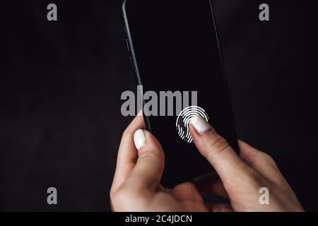 Hands holding smartphone with fingerprint scanner in the screen. Stock Photo