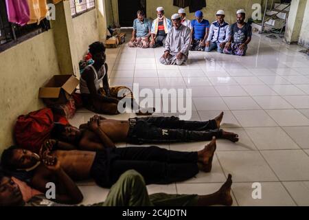 Lhokseumawe, Indonesia. 27th June, 2020. Migrant men rest at a temporary shelter in the immigration detention centre.Dozens of Rohingya people were rescued at sea by Indonesian fishermen while drifting on a broken boat in waters off Seunuddon in North Aceh. Credit: SOPA Images Limited/Alamy Live News Stock Photo