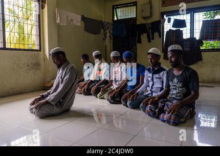 Lhokseumawe, Indonesia. 27th June, 2020. Migrant men pray at a temporary shelter in the immigration detention centre.Dozens of Rohingya people were rescued at sea by Indonesian fishermen while drifting on a broken boat in waters off Seunuddon in North Aceh. Credit: SOPA Images Limited/Alamy Live News Stock Photo