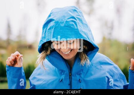 woman stood in the rain smiling outside in a raincoat Stock Photo