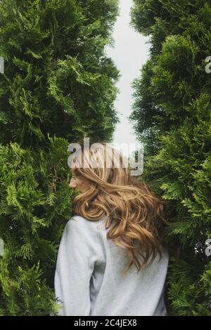 back view of young woman standing between cypresses Stock Photo