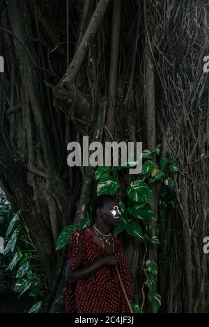 Maasai Man in traditional clothes standing in the forest Stock Photo