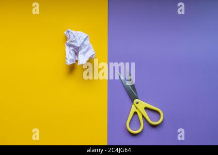 Yellow scissors isolated and a paper on a purple and yellow background. Copy space for text. Stock Photo