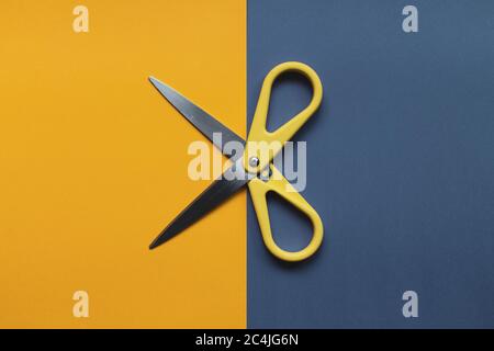 Yellow scissors isolated on a blue and yellow background. Copy space for text. Stock Photo