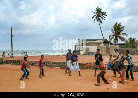 Muslim boys play a game of cricket on land adjacent to Negombo beach in Sri Lanka at dawn. Stock Photo