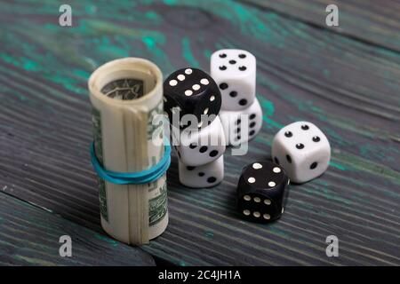 Dices are white and black. Near dollars rolled up in a tube. On brushed pine boards. Stock Photo