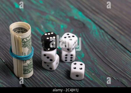 Dices are white and black. Near dollars rolled up in a tube. On brushed pine boards. Stock Photo