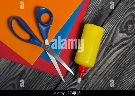 Stationery. Colored paper, scissors and glue. On brushed pine boards. Stock Photo