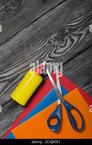 Stationery. Colored paper, scissors and glue. On brushed pine boards. Stock Photo