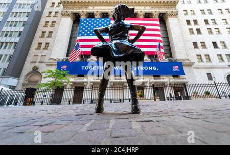 Manhattan, New York, USA - May 31, day, 2020: Rear view of Bronze statue - Fearless girl, looking up at the New York Stock Exchange building on Broad Stock Photo