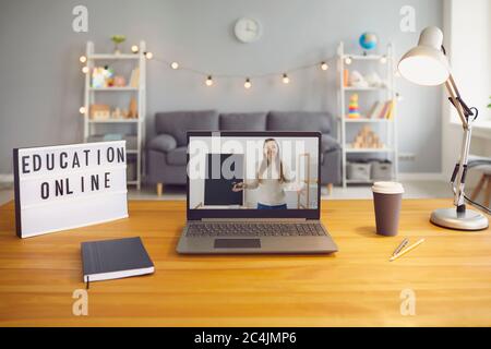 Online education. Laptop computer with young teacher giving class through webcam on screen standing on desk at home Stock Photo