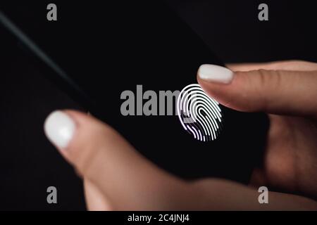 Hands holding smartphone with fingerprint scanner in the screen. Stock Photo