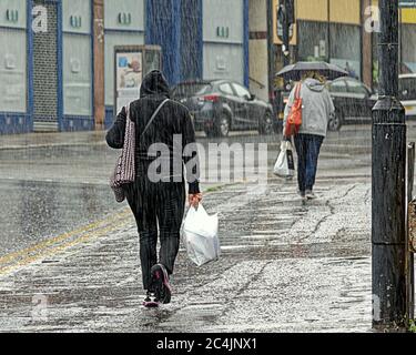 Glasgow, Scotland, UK 27th  June, 2020: UK Weather: Heavy rain with the summer twist of being warm fell on a city swarming with police as locals went about their umbrella holding business. Gerard Ferry/Alamy Live News Stock Photo