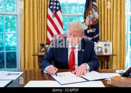 Washington, United States Of America. 27th June, 2020. President Donald J. Trump signs a Presidential Proclamation on Suspension of Entry of Immigrants and Nonimmigrants Who Present a Risk to the United States Labor Market During the Economic Recovery Following the 2019 Novel Coronavirus Outbreak Monday, June 22, 2020, in the Oval Office of the White House People: President Donald Trump Credit: Storms Media Group/Alamy Live News Stock Photo