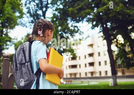 Happy little student girl with a backpack on her way to school. Stock Photo