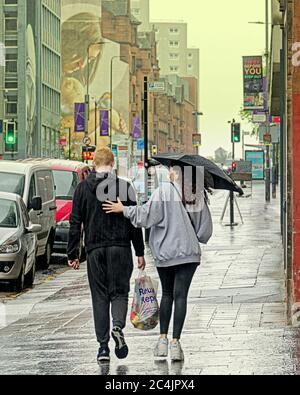 Glasgow, Scotland, UK 27th  June, 2020: UK Weather: Heavy rain with the summer twist of being warm fell on a city swarming with police as locals went about their umbrella holding business. Gerard Ferry/Alamy Live News Stock Photo