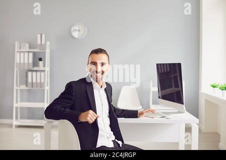 A brunette man in a black jacket sitting at the table works with papers in the office. Stock Photo