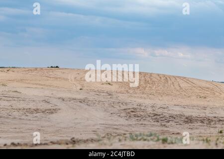 Desert in spring distant view on sand dunes near forest with epic dark sky. Kitsevka desert hilly sands in Ukraine, Kharkiv region landscape Stock Photo