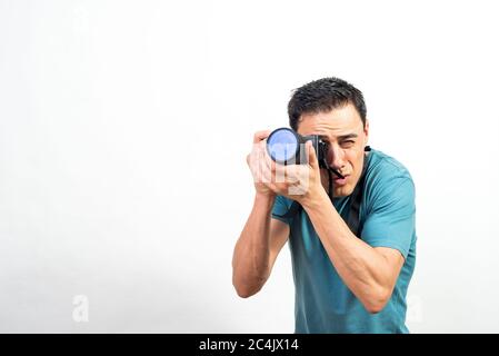Man with photo camera photographing something very concentrated, looking straight ahead. Mid shot. White background. Stock Photo