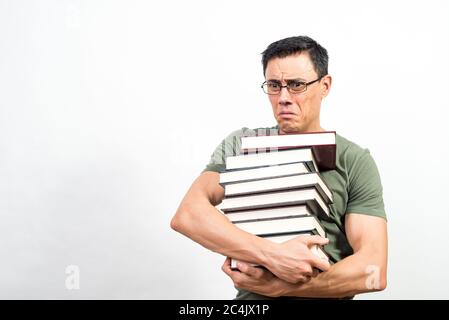 Very worried student with glasses holding a lot of books. Mid shot. White background. Stock Photo
