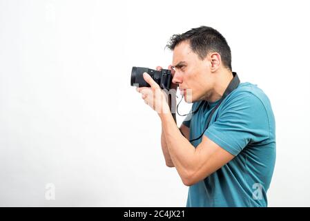 Man with photo camera photographing something very concentrated, side view. Mid shot. White background. Stock Photo