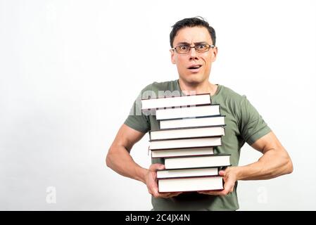 Very worried student with glasses holding a lot of books. Mid shot. White background. Stock Photo