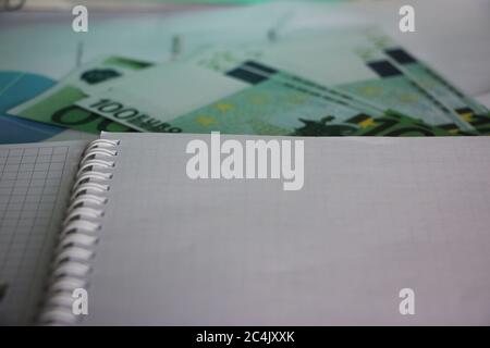 One hundred euro banknotes and blank page of spiral copybook. Profitable business concept Stock Photo