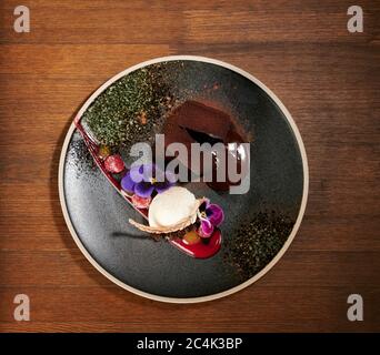 Tasty brownie and ice cream dessert on black plate above top view Stock Photo