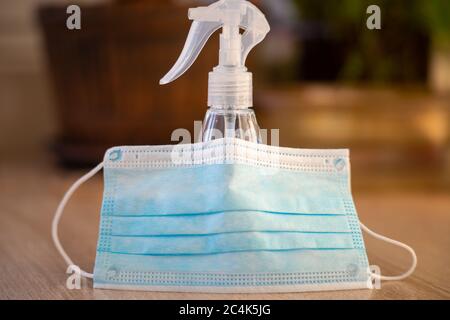 Close-up on hand sanitizer bottle and a disposable face mask on a wooden table. Anti bacterial gel. Stock Photo