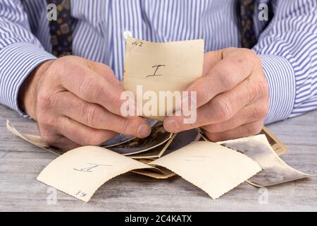 an elderly man holding curled old black and white photographs in his rough hands Stock Photo